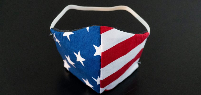 A handmade fabric face mask featuring the stars and stripes of the American flag on a black background.