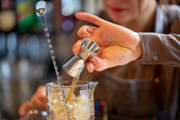 woman bartender with jigger as tool for pouring