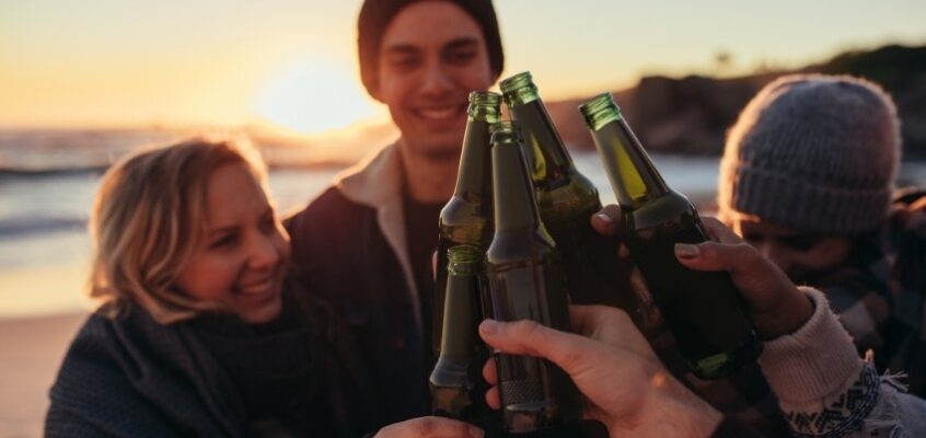 friends clinking beer on the beach