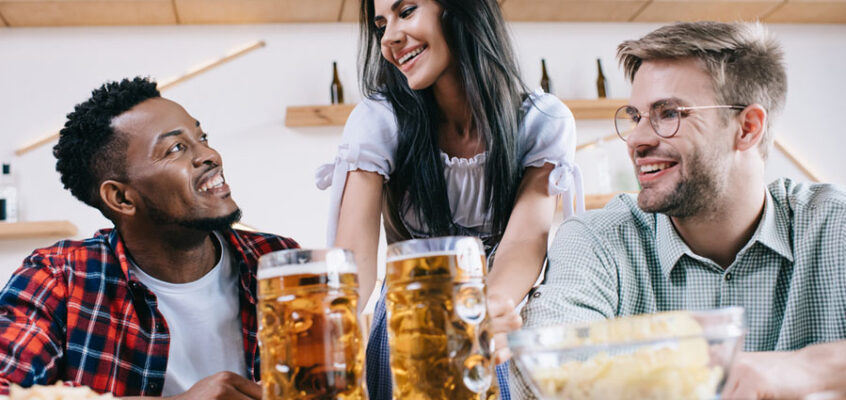 cheerful server serving beer in a restaurant in a traditional German costume