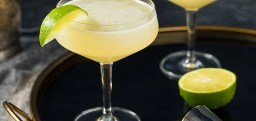 A chilled gimlet cocktail in a coupe glass garnished with a fresh lime wedge.