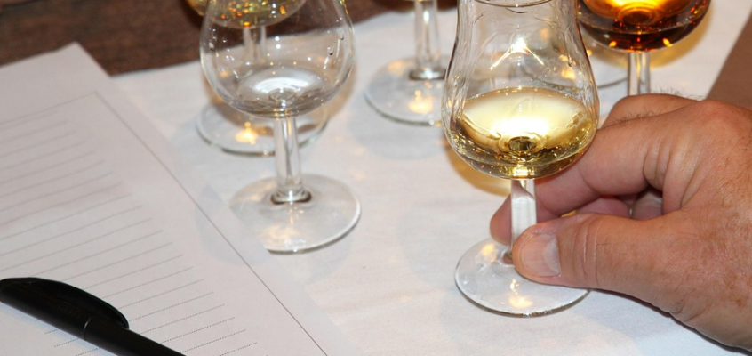 Four different glasses of alcoholic beverages, ranging from light to dark spirits/beer